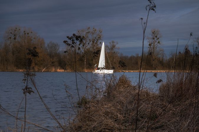 Sailboat on overcast day shot from the river bank
