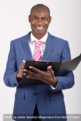 Smiling male in business attire standing and taking notes in folder 47AMz0
