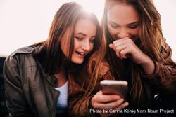 Two young women laughing at something on the phone o5oQQb