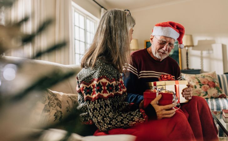 Older couple celebrating Christmas at home and exchanging presents