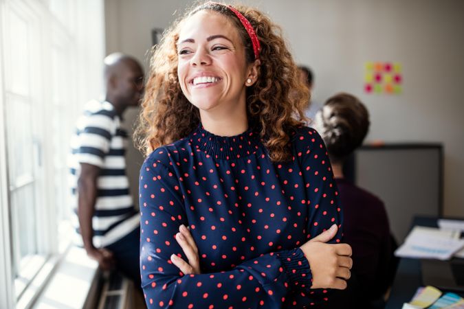 Woman smiling with arms folded looking out the window