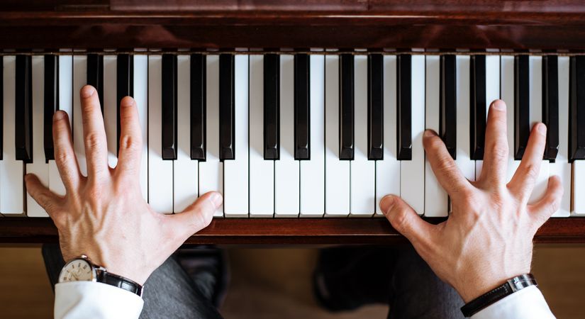 Crop male hands playing piano