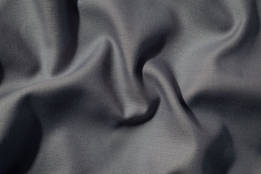 Crumpled wavy dark grey silky fabric background texture. siny and glossy.