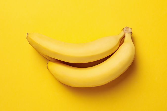 Banana cluster on yellow background. Fresh fruit