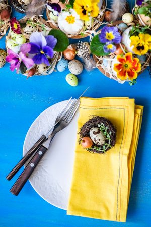 Top view of Easter holiday card concept with eggs and flowers on bright blue table