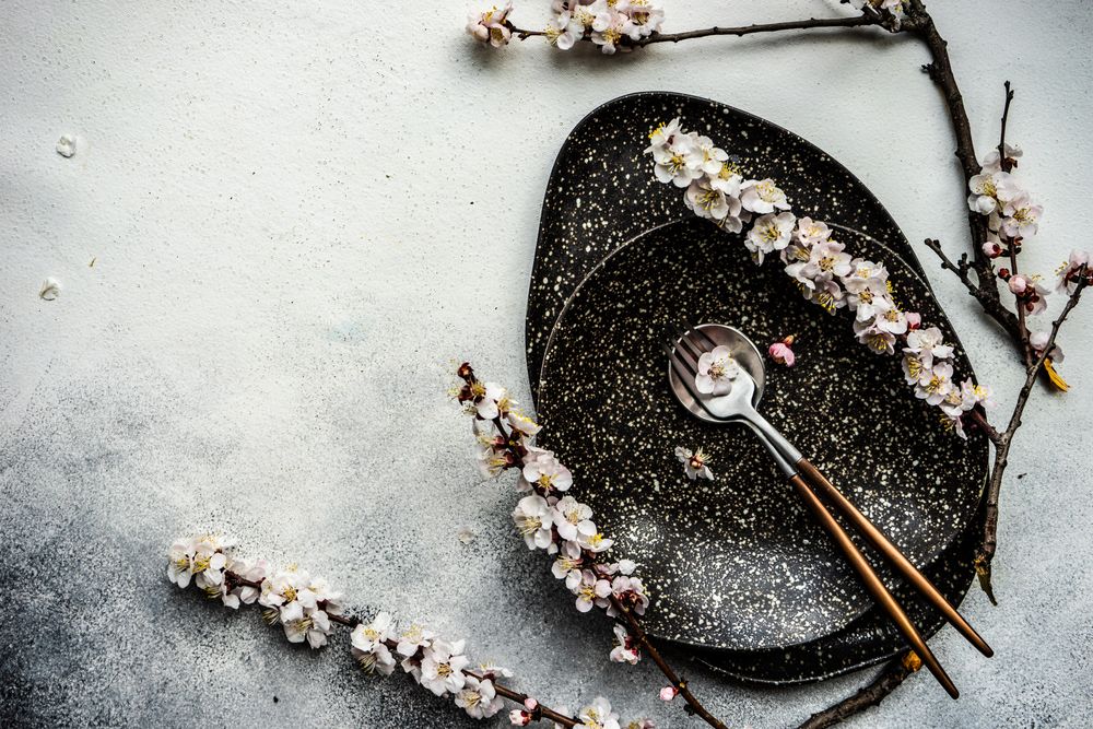 Minimalistic table setting with apricot blossom on elegant dark table setting
