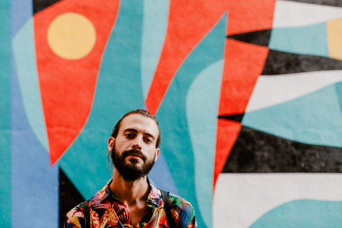 Cool bearded man in bright shirt against colorful wall