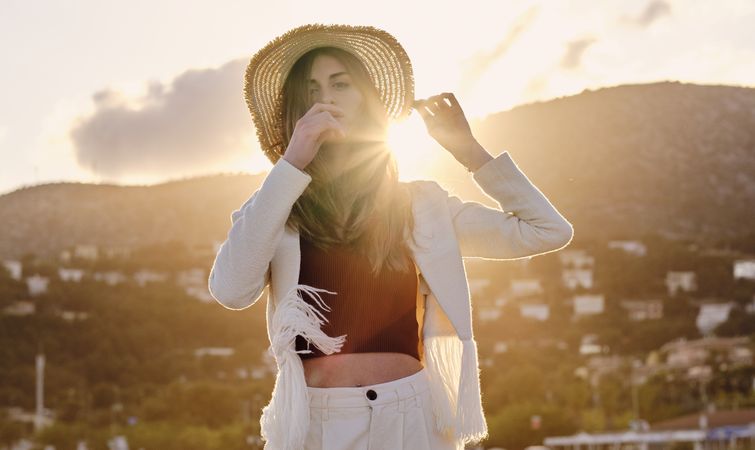 A long hair fashion model with a hat at the beach at sunset in a summer day