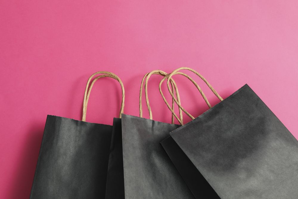 dark paper bags on pink background, space for text