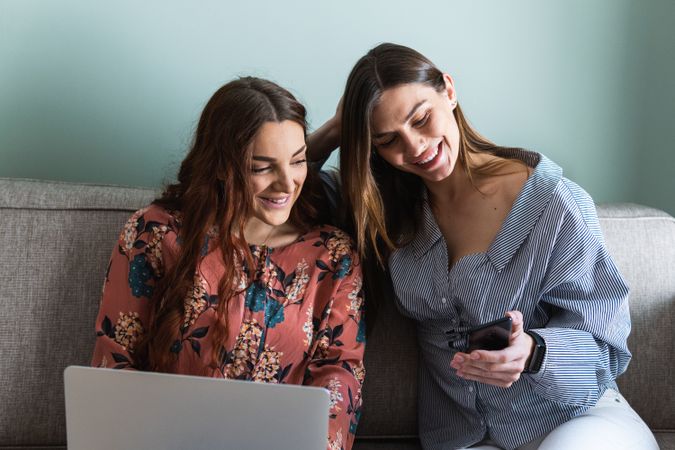 Young women resting on sofa and browsing smartphones