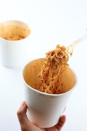 Woman's Hand Holding Plastic Fork Eating Instant Noodles
