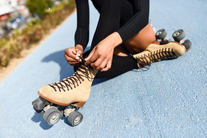 Woman putting on roller skates while sitting on cement