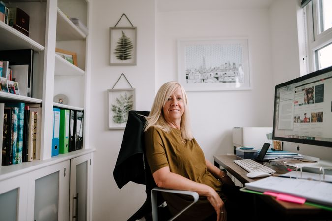 Mature woman with grey hair working from bright home office