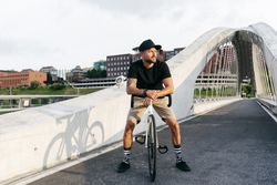 Cheerful man with bicycle standing on footbridge