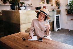 Young woman writing in a notebook at a coffee shop with a glass of water