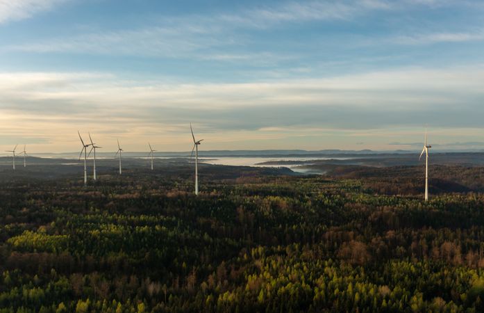 Drone view with wind turbines in a german forest at golden hour at sunrise