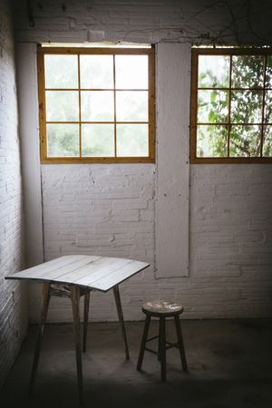 Concept of table near stool in grey murk room with brick walls