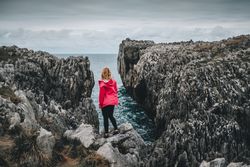 Female standing on cliff and contemplating