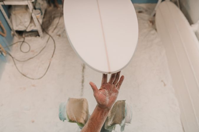 Man in respirator polishing surf board in workshop