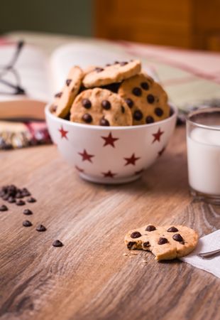 Chocolate chip cookies and milk on wood background