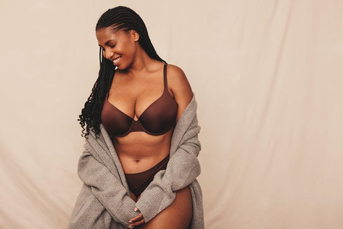 Beautiful woman with braids wearing brown undergarments and sweater in studio