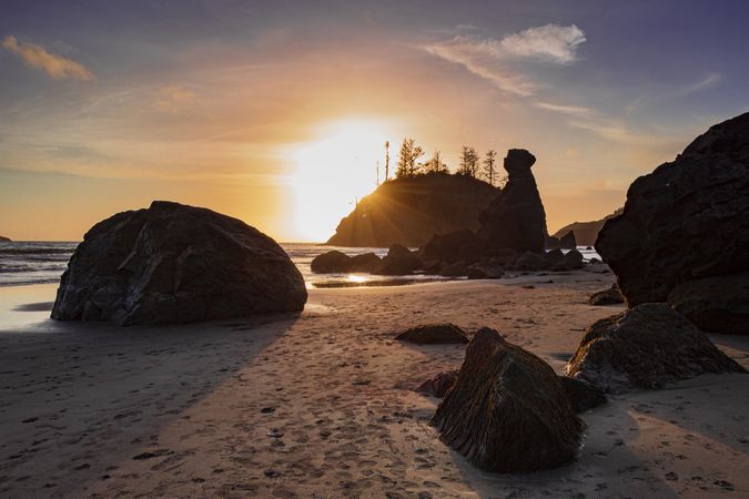 Beautiful quiet beach with sun coming behind the rocks