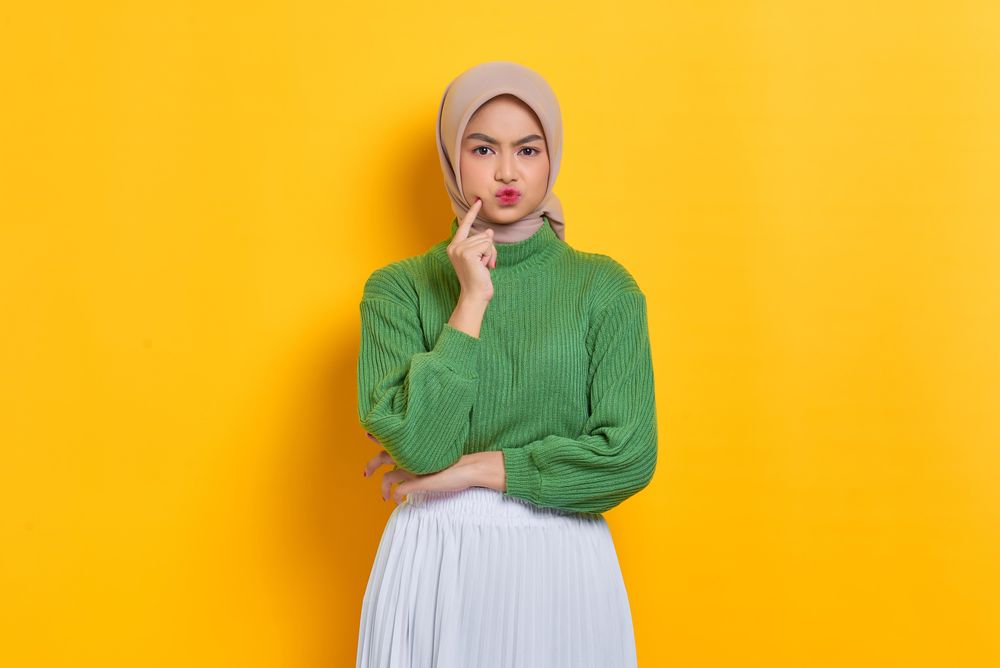 Pouting woman in headscarf with hand on cheek