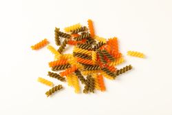 Color pasta on blank background, space for text. Dry uncooked whole pasta