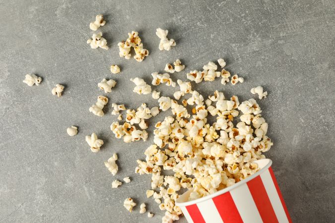 Flat lay composition with bucket and popcorn on grey background, copy space