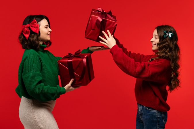 Woman and girl juggle large red boxes in holiday studio