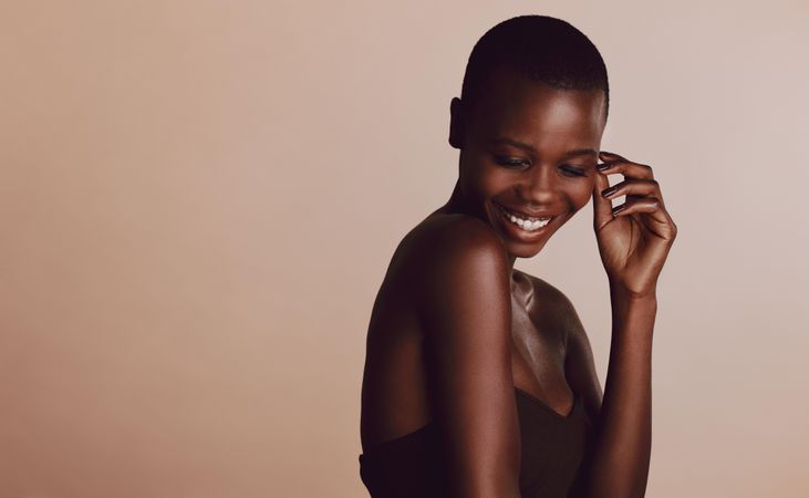 Black female model smiling against beige background