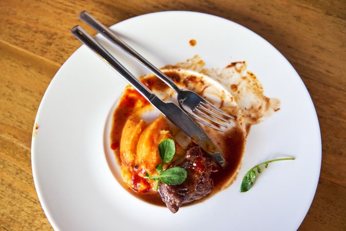 Forks on a plate with leftover food from a dish of veal cheeks w