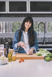Portrait of a housewife cooking while looking at camera in the kitchen at home