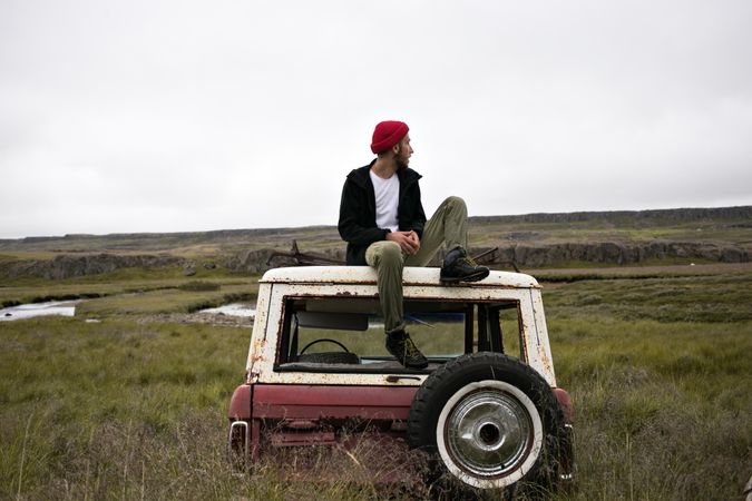 Man sitting on abandon vehicle