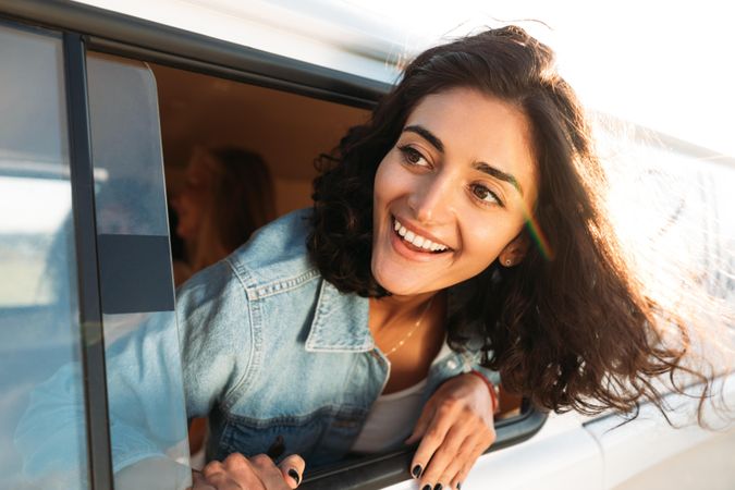 Curly haired woman with her head out of a car’s window