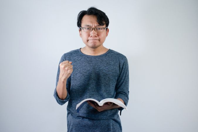 Asian student holding books and making strong gesture