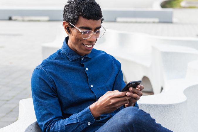 Attentive hispanic businessman chatting on smartphone in town