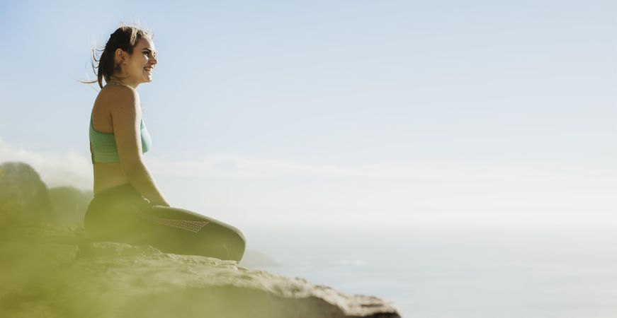 Healthy woman sitting on a cliff overlooking the view