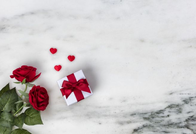 Valentine’s Day celebrated with red roses and giftbox on marble stone background