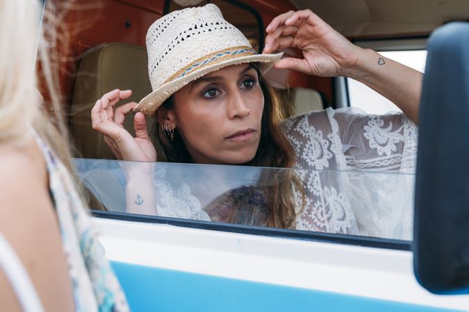 Smiling woman in hat in front seat of car opening door