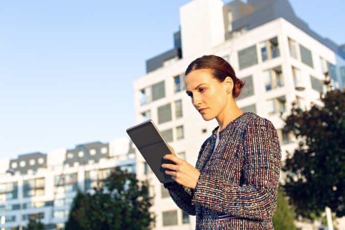 Confident entrepreneur with tablet on city street