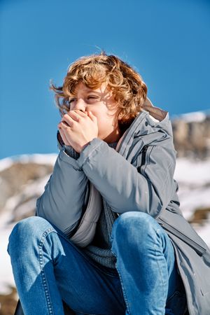 Little boy sitting on snowy mountain slope