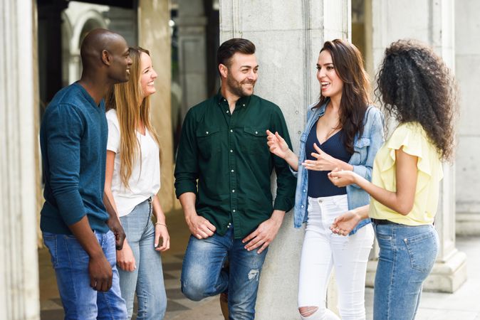 Group of women and men talking together by city pillar