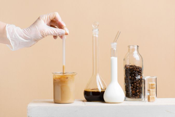 Woman’s hand testing iced coffee in coffee lab