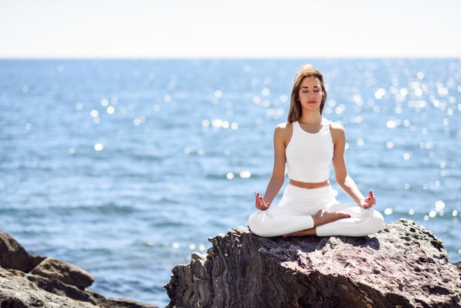 Young woman meditating on the beach with her legs crossed