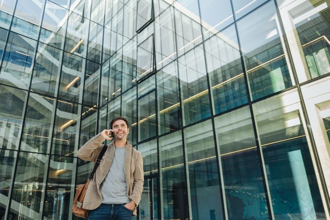 Smiling entrepreneur using smartphone outside office building