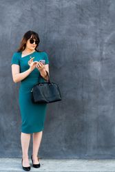 Chic transgender woman in blue dress texting outside