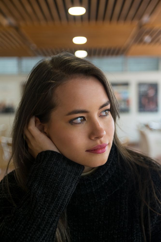 Woman sitting along bookshelves and looking away