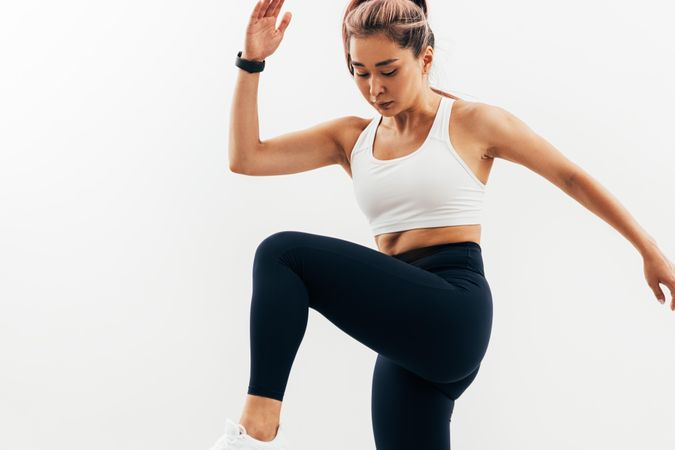 Woman exercises reaching her knee to her elbow