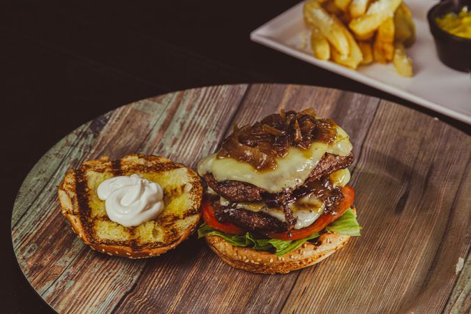 Double cheeseburger with onions on wooden plate